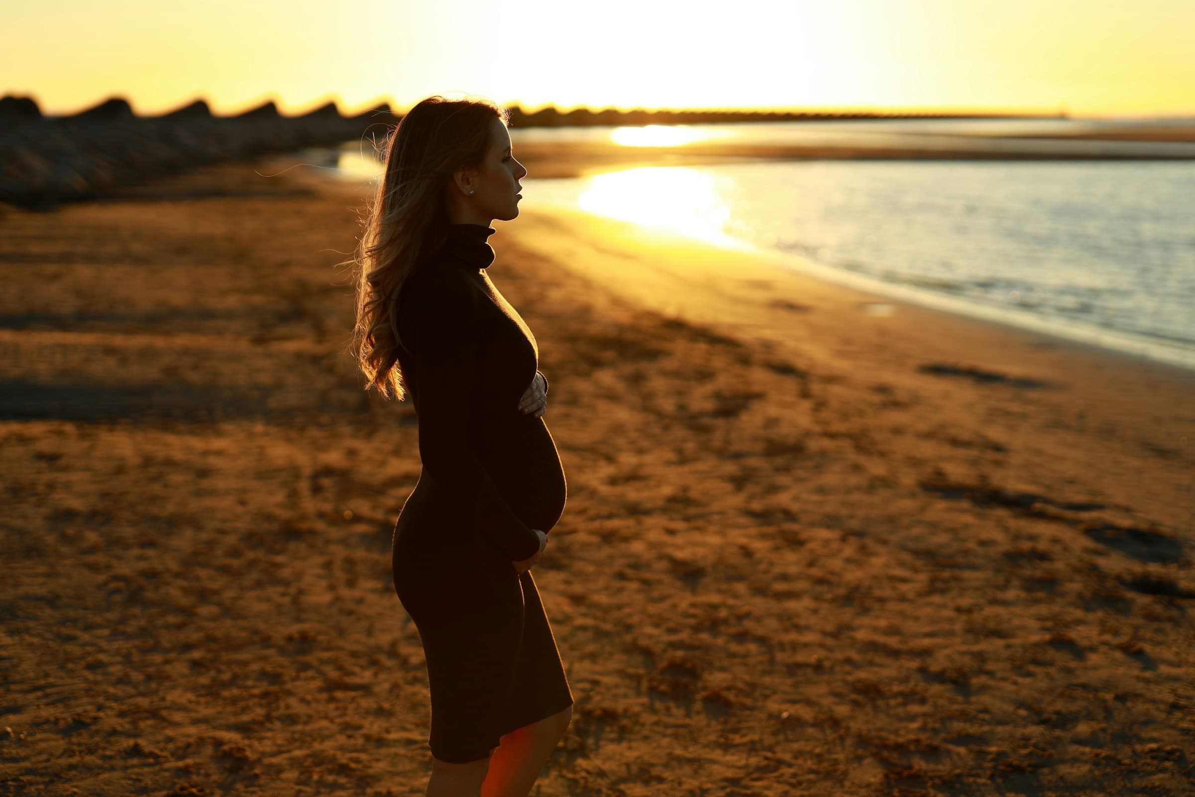 A pregnant woman faces the shore
